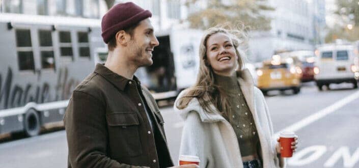 Couple walking on the street and holding a red cup