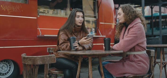 Two friends in deep conversation in front of a food truck