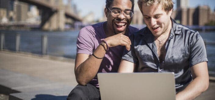 Two guys laughing in front of a laptop