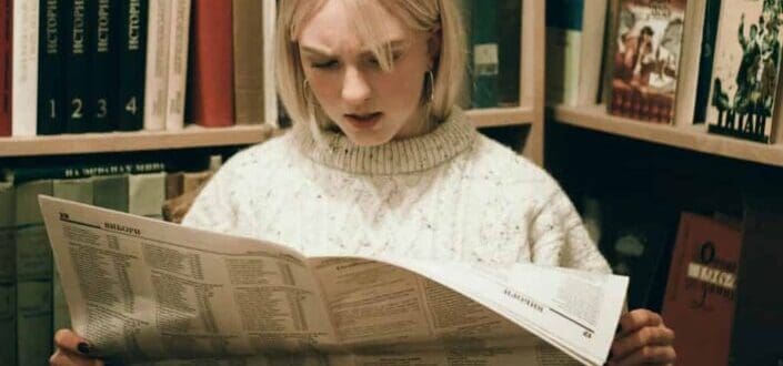 Girl reading a newspaper with a shocked face