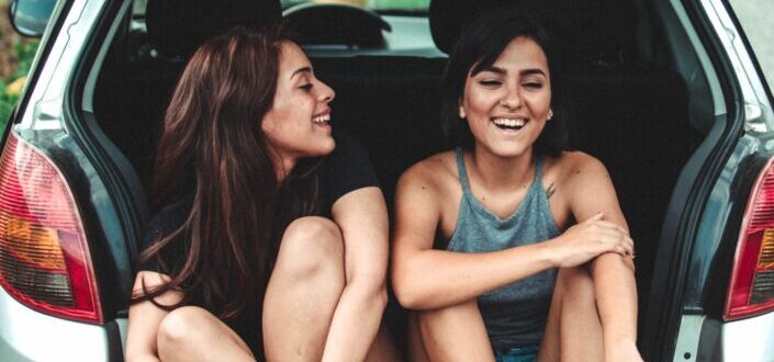 Two girls sitting on trunk