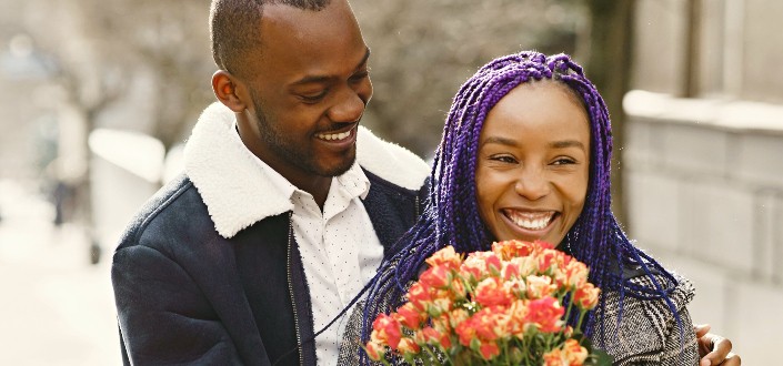 couple smiling while the woman holds flowers