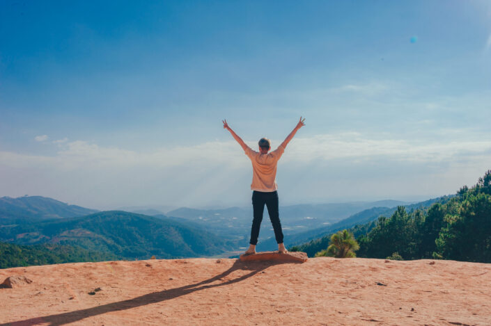 Girl raising both hands in the air over a mountain