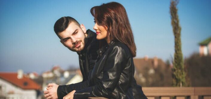 Man and Woman Talking on a Terrace Leaning on a Railing