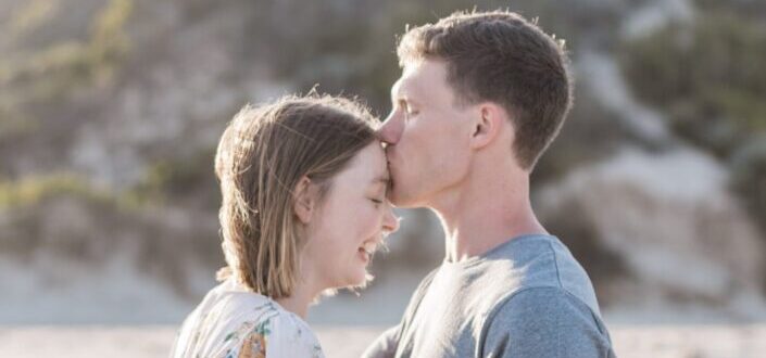 A man kissing a happy woman's forehead