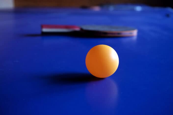 Yellow ping pong ball and paddle on a blue table