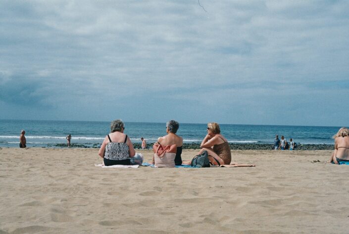 Three senior ladies sitting on a beach