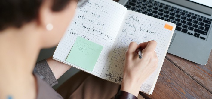 Woman scribbling notes on an open notebook