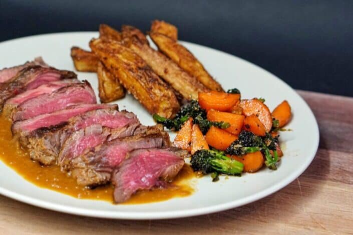 Cooked meat with green vegetable on white ceramic plate