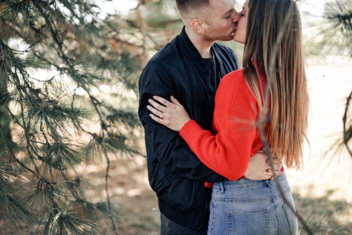 A couple kissing in between trees
