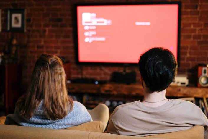 A couple sitting down and watching the tv