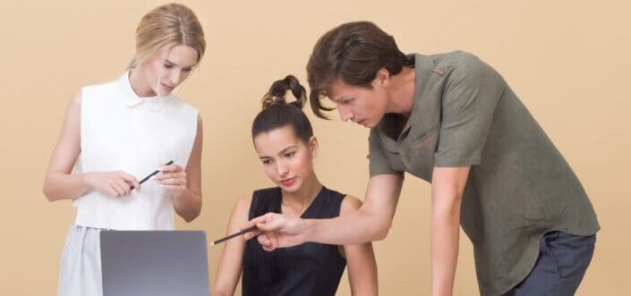 Three people discussing something on a laptop