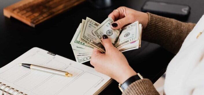 Crop woman counting money at modern office table