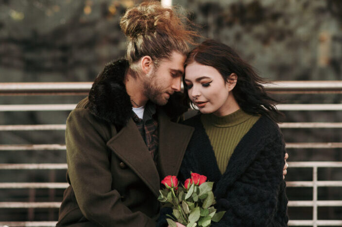 A couple sitting together while holding roses