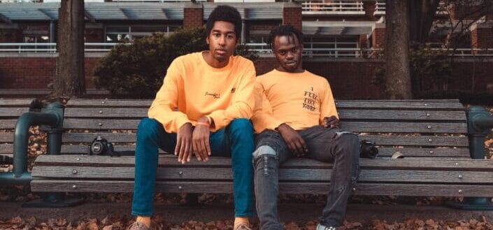 Two men wearing yellow sitting on bench