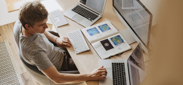 Man working on three computers