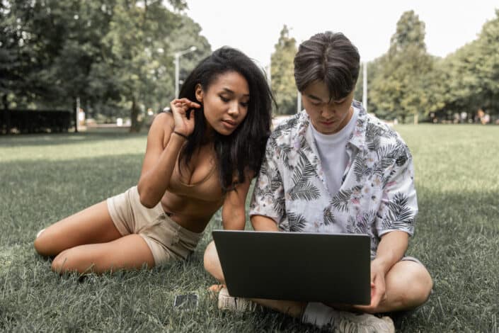 Multiracial couple surfing laptop in countryside