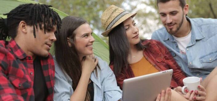 Group of friends smiling in front of a tablet