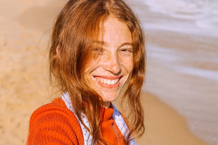 smiling woman with freckles standing by the beach