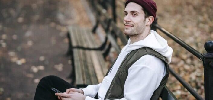 Smiling man with smartphone on bench