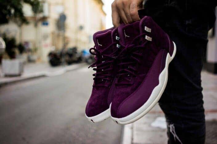 A man holding a pair of purple sneakers