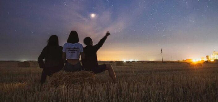 Friends on haystack, guy pointing to the sky.