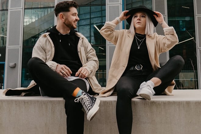 Couple wearing matching clothes sitting on a ledge - unanswerable questions