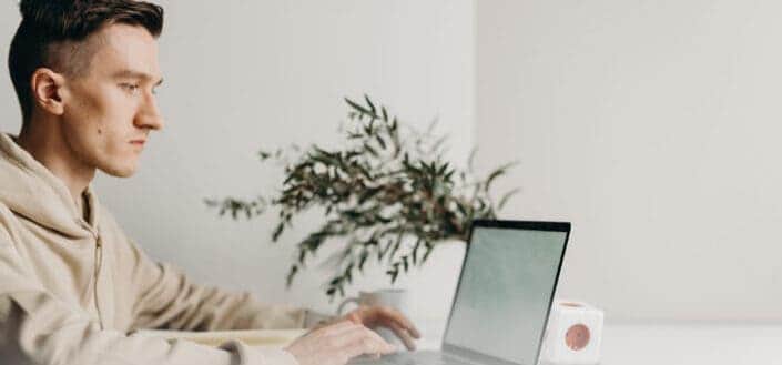 man in gray sweater using macbook pro