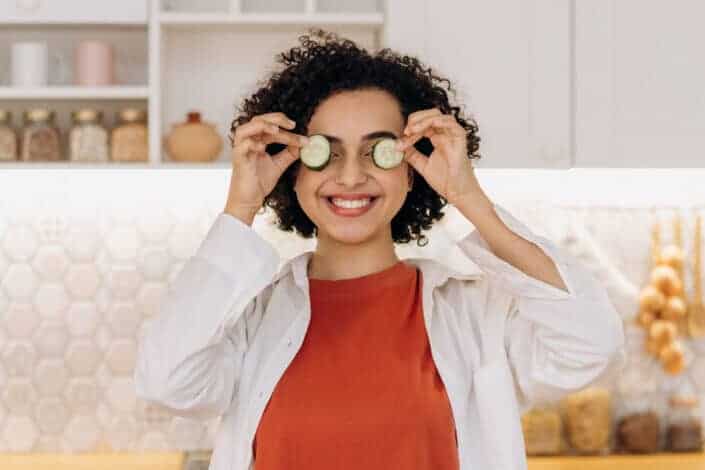 Woman putting slices of cucumber on her eyes