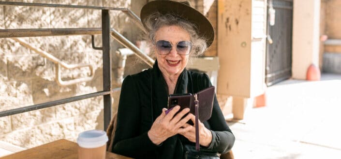 elderly woman in black holding black smartphone