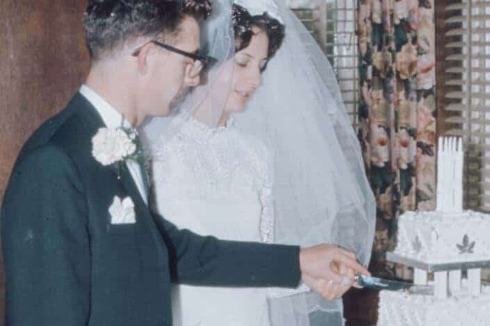 A newlywed couple slicing their wedding cake