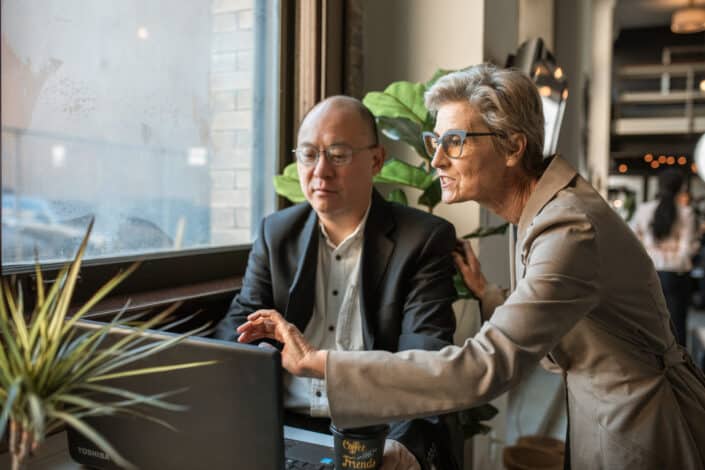 An old man and woman looking at the computer