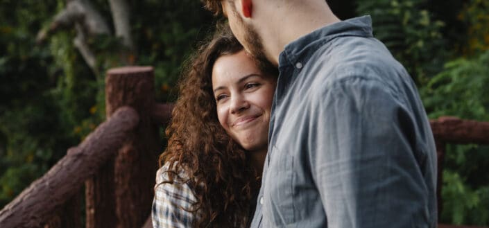 man kissing the forehead of smiling girlfriend