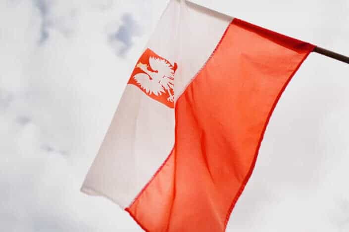 Colorful flag of republic of Poland under cloudy sky