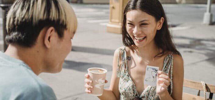 Happy ethnic woman showing photo to boyfriend