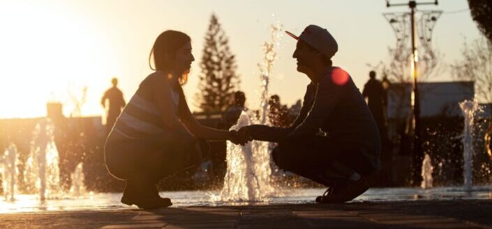 couple sitting on water fountain during sunset