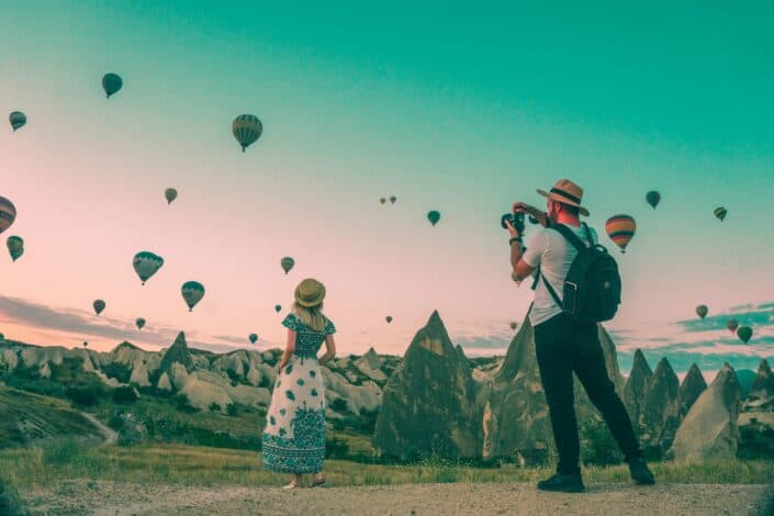 Man taking photos of woman with hot air balloons