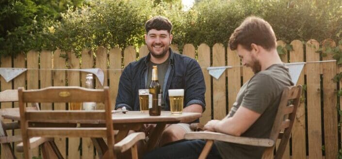 cheerful men chatting on backyard and drinking beer