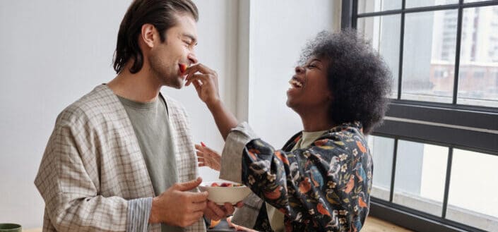 Woman feeding strawberries to a man and laughing
