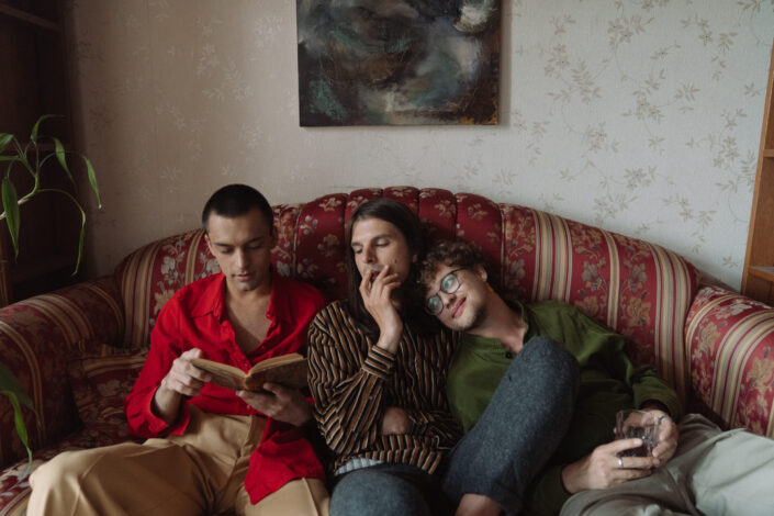 Three men sitting on couch while reading book