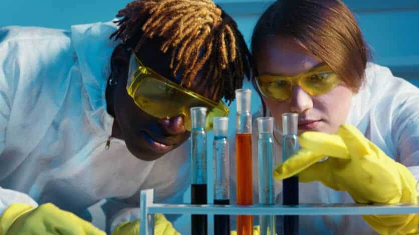 A man and a woman looking at the test tubes, experimenting