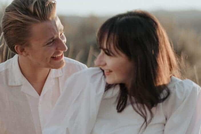 happy newlyweds with flowers sitting in nature