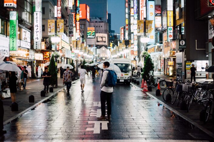 a busy street with peoples and cars on a rainy day