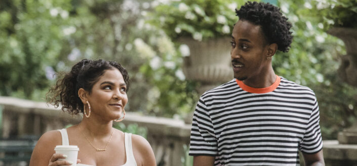 Positive multiracial couple walking with takeaway coffee