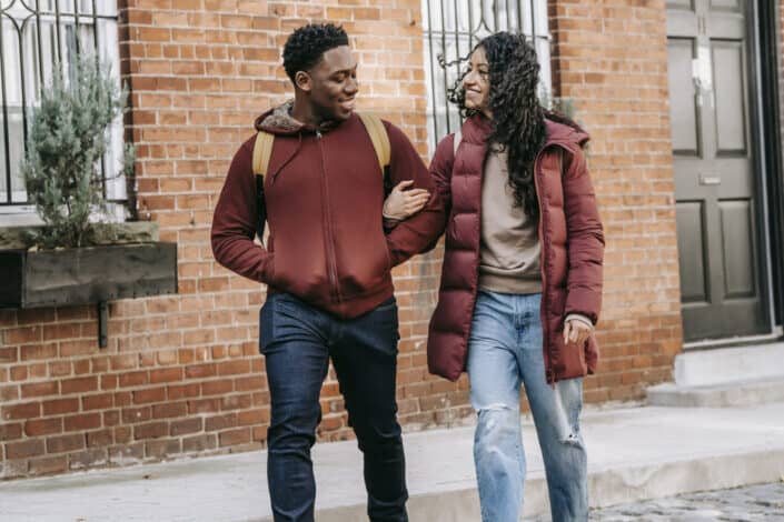 glad multiethnic couple walking on street