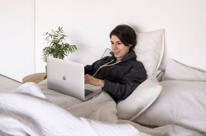 woman using her laptop on her bed