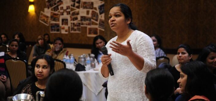 Woman in white asking question using a microphone.