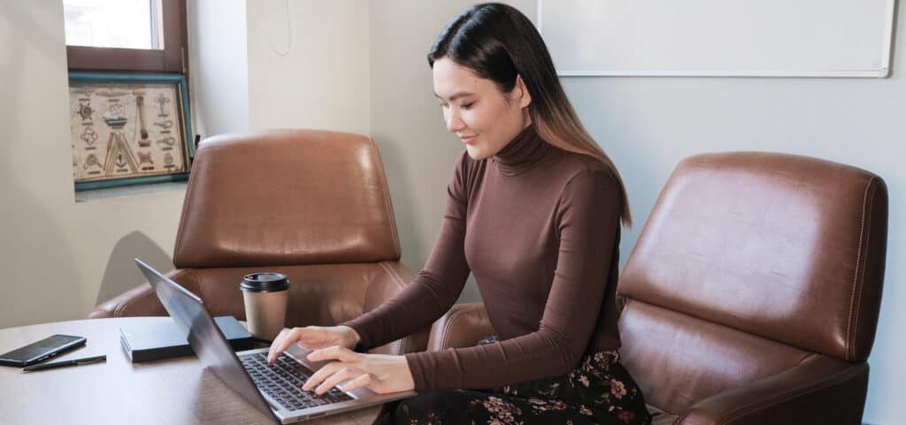 Finely dressed-up female employee typing on laptop.