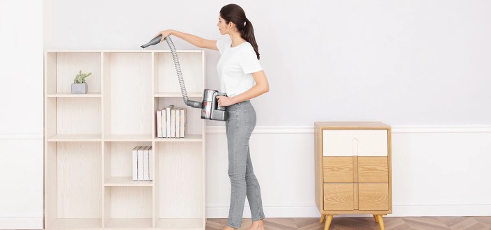 lady cleaning the top of a shelf using an electric cleaner