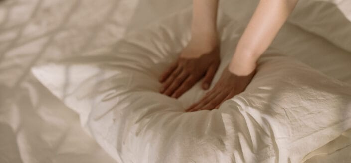 hands pushing down on soft white pillow